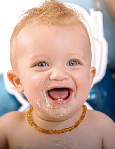 Cake smash photography: An adorable baby gleefully smashing a colorful birthday cake with their hands, surrounded by festive decorations and laughter, capturing the joy and excitement of their first birthday celebration.