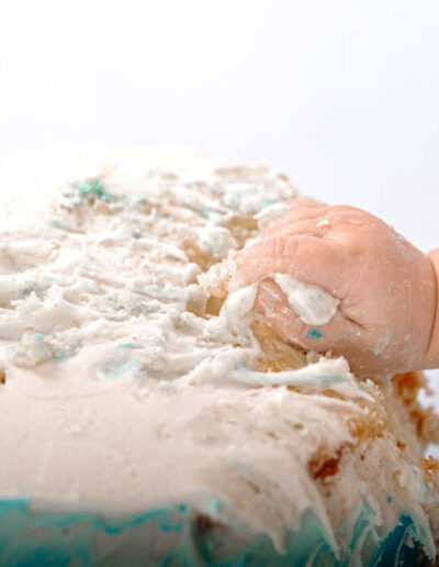 Cake smash photography: An adorable baby gleefully smashing a colorful birthday cake with their hands, surrounded by festive decorations and laughter, capturing the joy and excitement of their first birthday celebration.